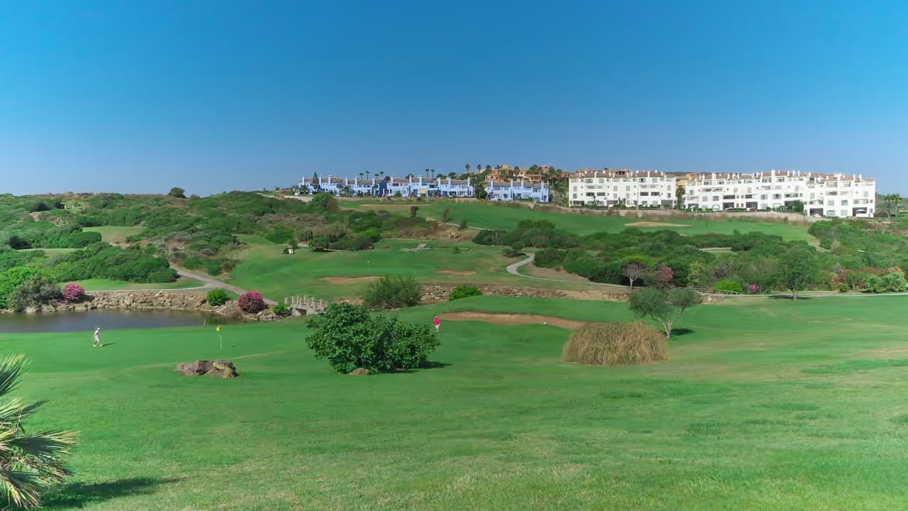 SERENITY FRONTLINE GOLF HOMES AND BEACH CLUB : parcours de golf La Alcaidesa Heathland, paysage méditerranéen et bâtiments résidentiels au loin à La Alcaidesa, Costa del Sol