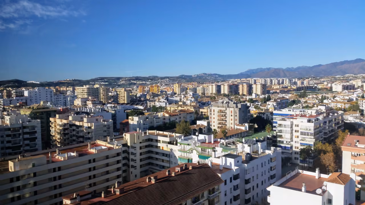NOVA MARINA: Panoramisches Luftbild des Wohn- und Geschäftsgebiets im westlichen Fuengirola mit der Sierra de Mijas im Hintergrund, Andalusien, Spanien