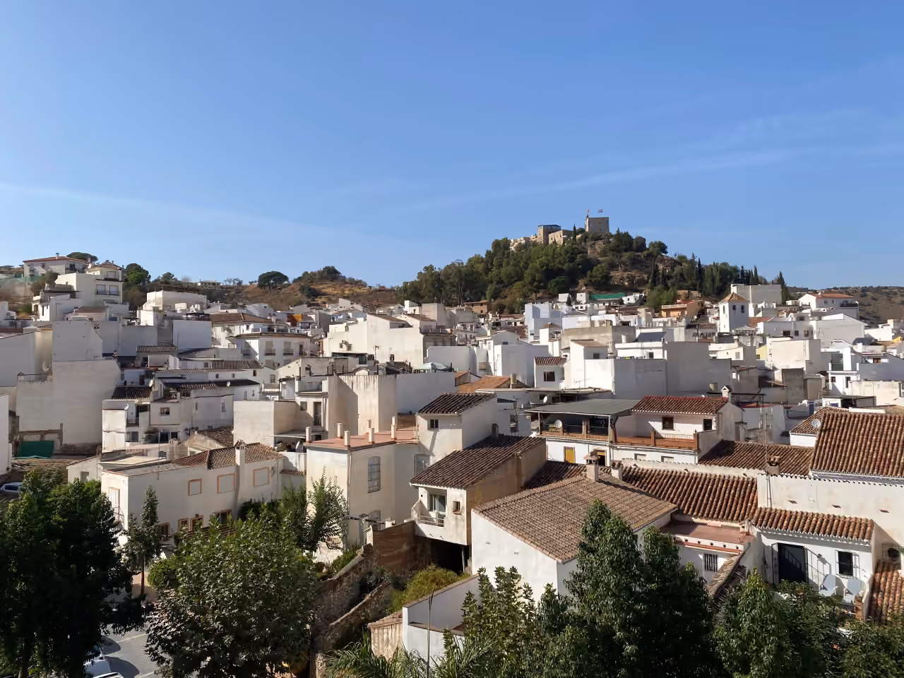 Gebiedsfoto bij LUNA NOVA RESIDENCES van het witgekalkte dorp Monda en de kasteel/kerk op de heuveltop in de provincie Málaga, Andalusië, Spanje