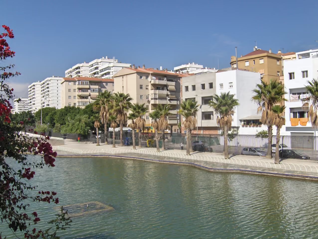 A MILABEKA környékét bemutató fénykép a Parque del Oeste taváról, a pálmafás sétányról és a Parque Mediterráneo lakónegyedről, Málaga