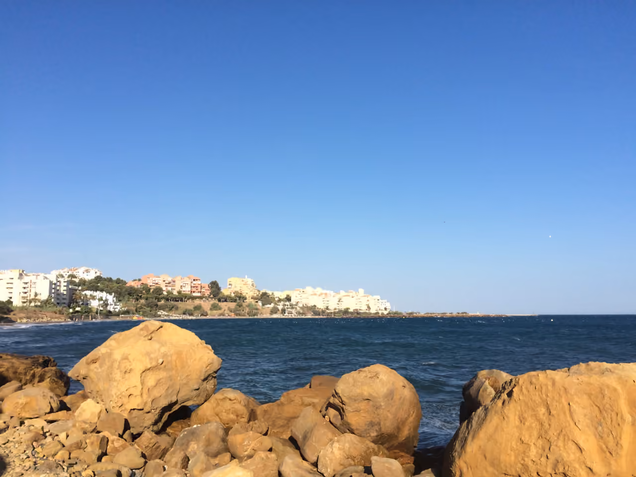 Områdesfoto nära COSTAFIORE GARDENS - FASE 1 med Esteponas klippiga strandpromenad, Medelhavet och kustens bostadsbebyggelse under klarblå himmel