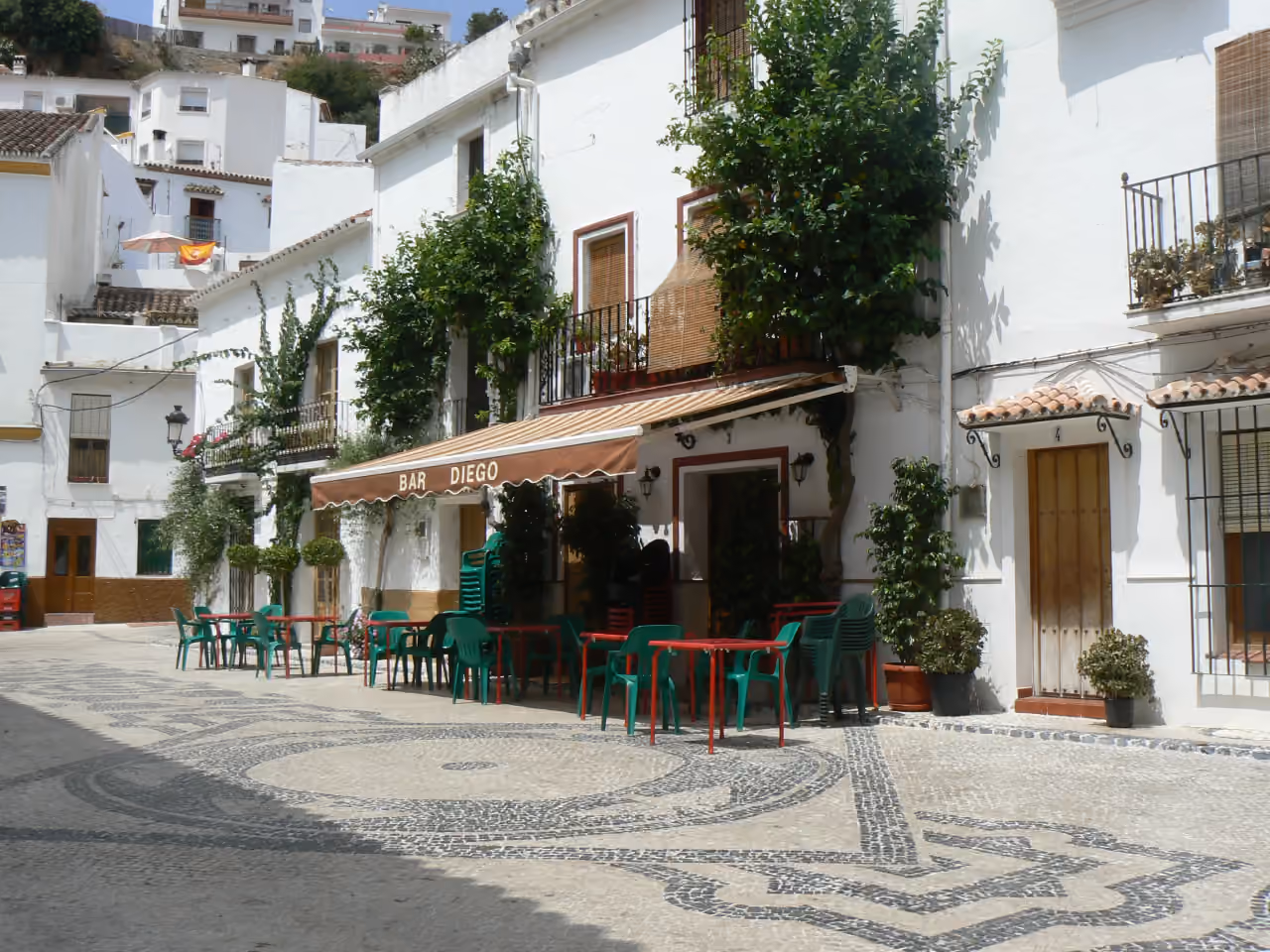 CALLE MIRÓ: traditionelt hvidkalket landsbytorv (plaza) i Ojén med mosaikbelagt brostensbelægning og barterrasse, Andalusien, Spanien